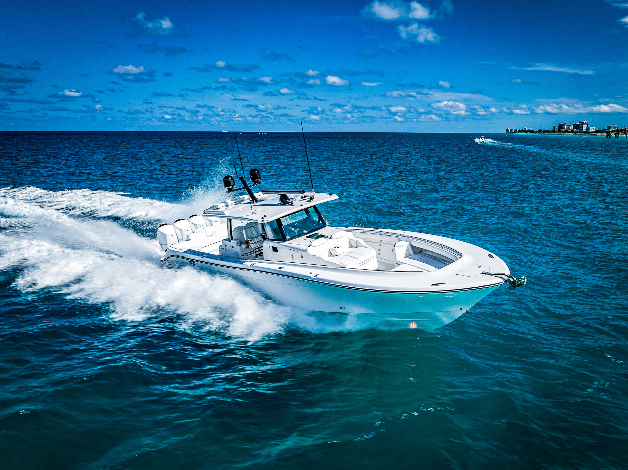 HCB 53 Sueños RXV — teal hull running hard port quarter, white upholstery, South Florida