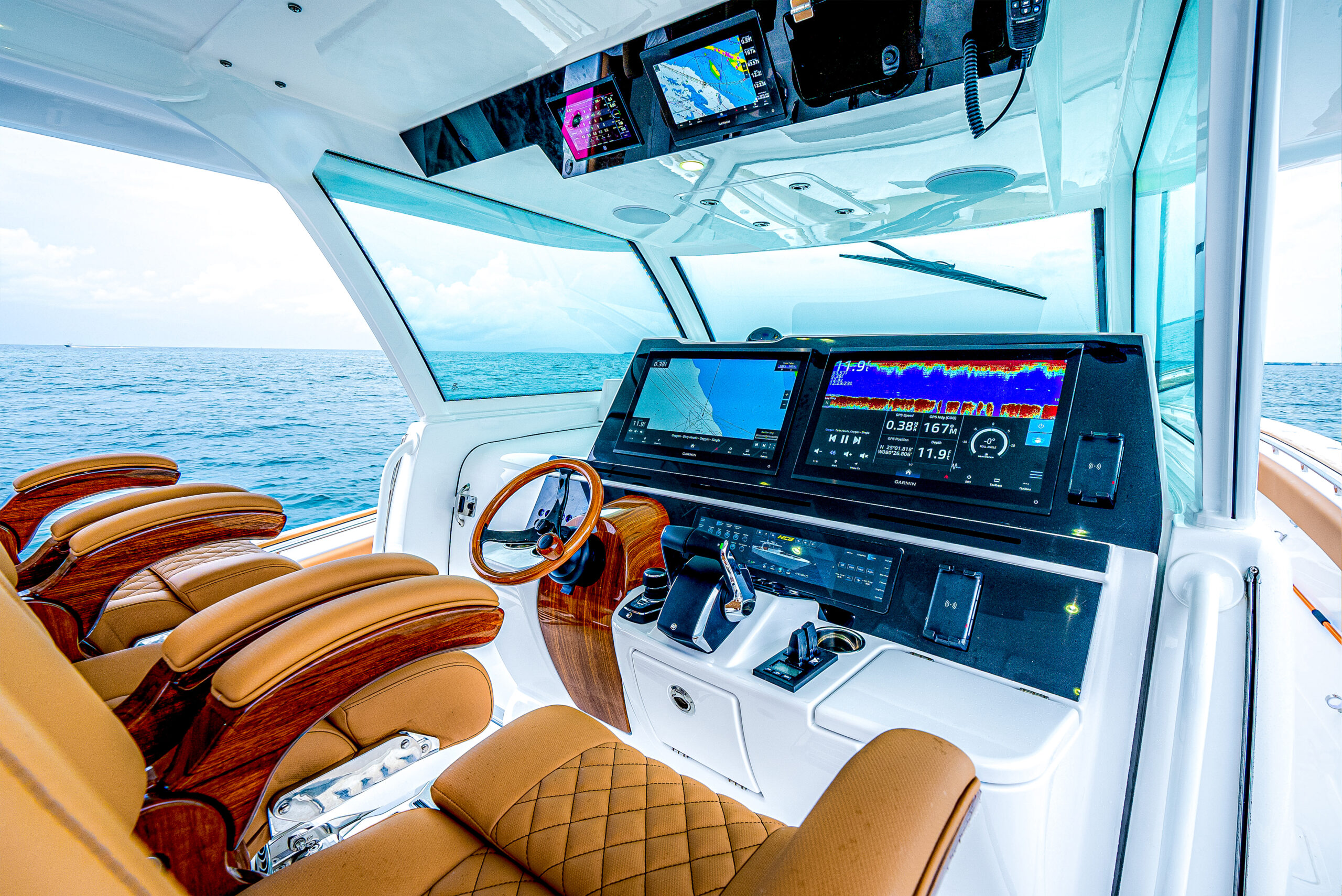 HCB 56 Sueños GIX helm — dual Garmin MFDs, teak wood wheel, tan captain chairs, panoramic glass