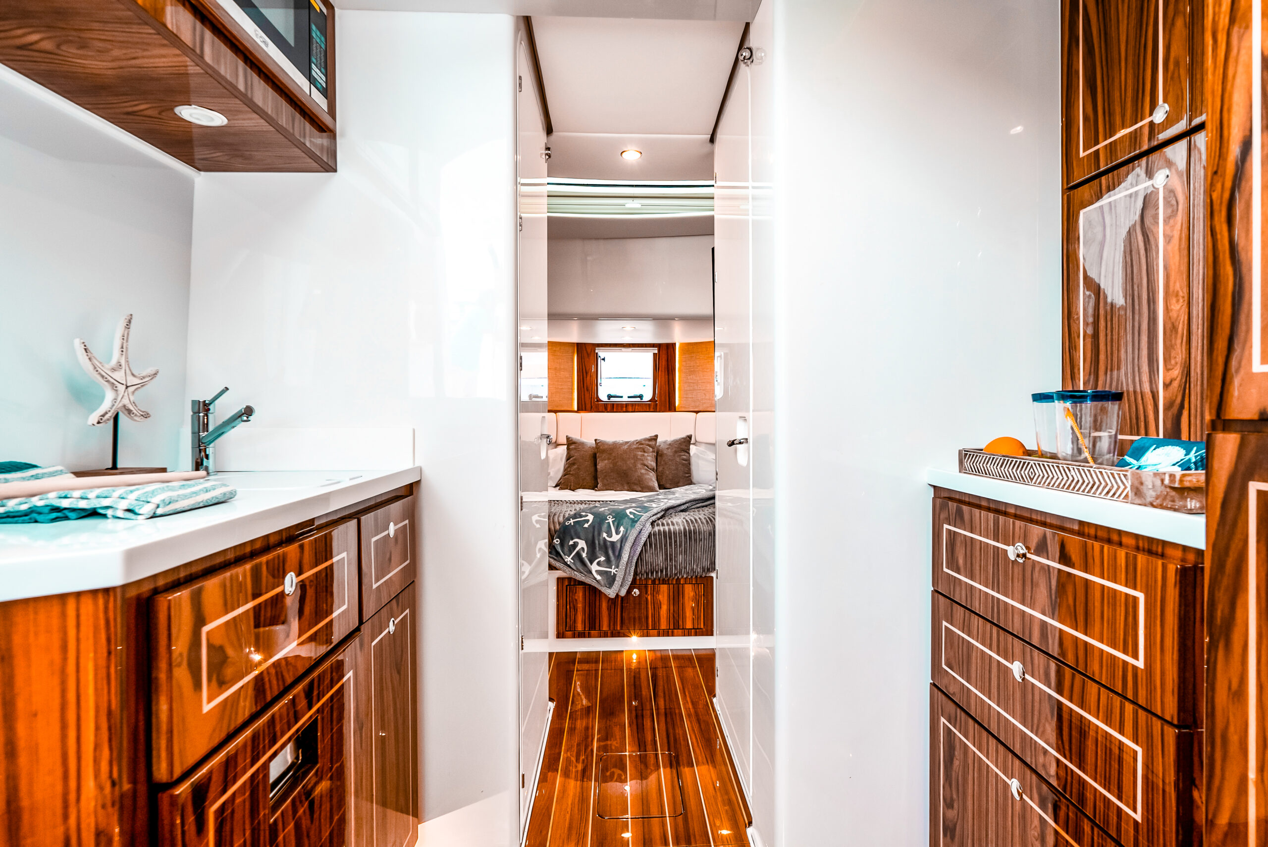 HCB 56 Sueños GIX salon — L-shaped settee with TV, teak staircase, high-gloss wood cabinetry, teak sole