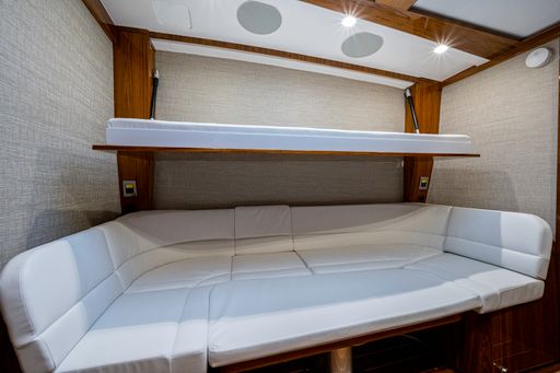 HCB 65 Estrella — water-level bow shot, spray flying, sole helmsman, blue skies