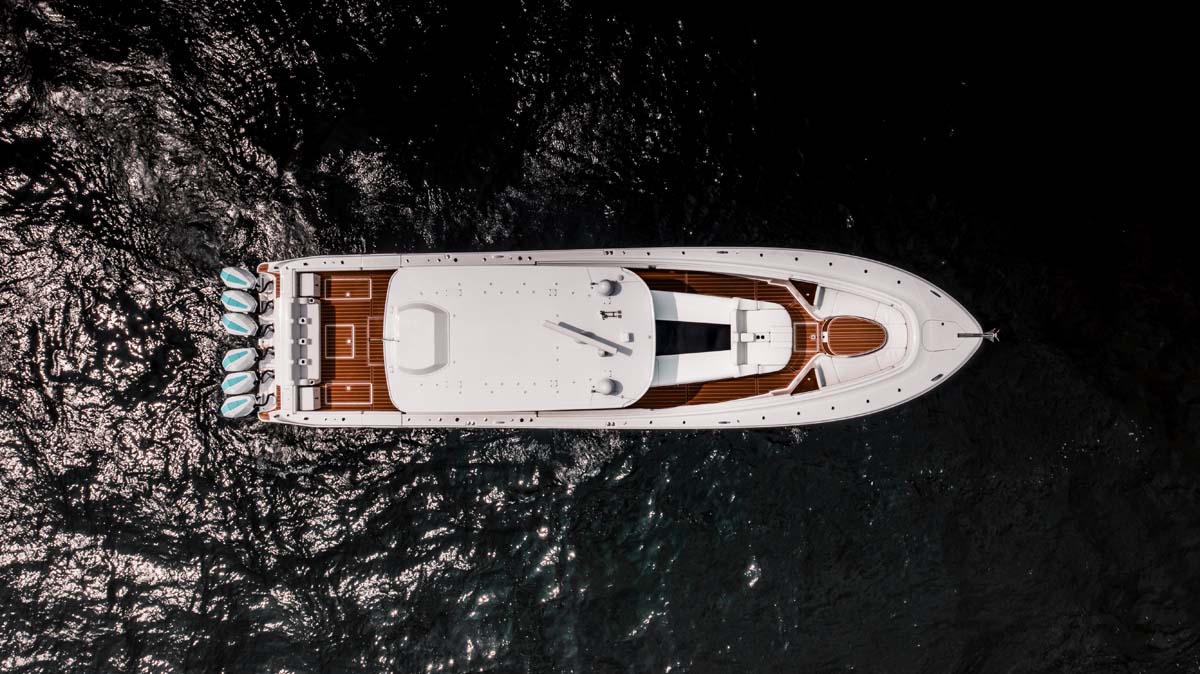 HCB 65 Estrella helm close — HCB gold badge, teak column, twin Garmin MFDs, joystick