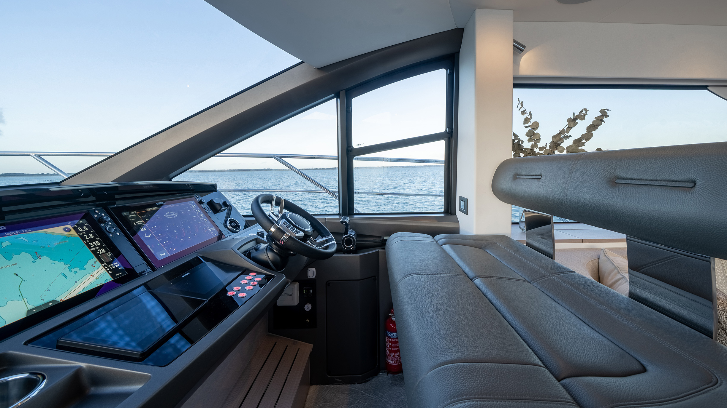 Sunseeker Manhattan 56 — helm face-on, dual Simrad MFDs, panoramic windscreen, Dorset coast