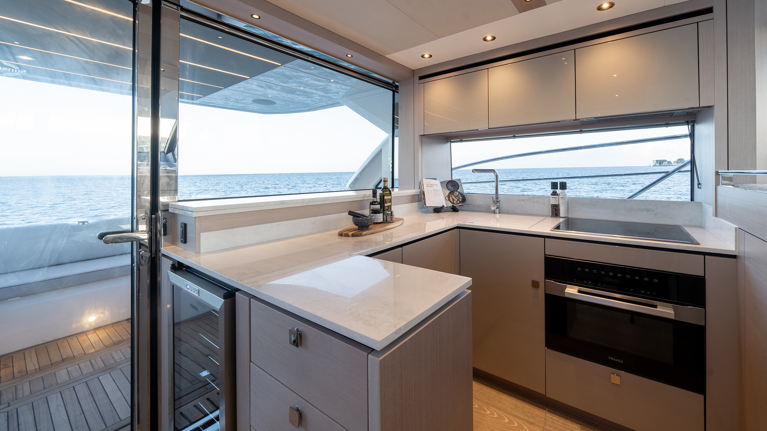 Sunseeker Manhattan 56 — full-width aft galley, Miele oven, wine cooler, stone countertops, open cockpit door