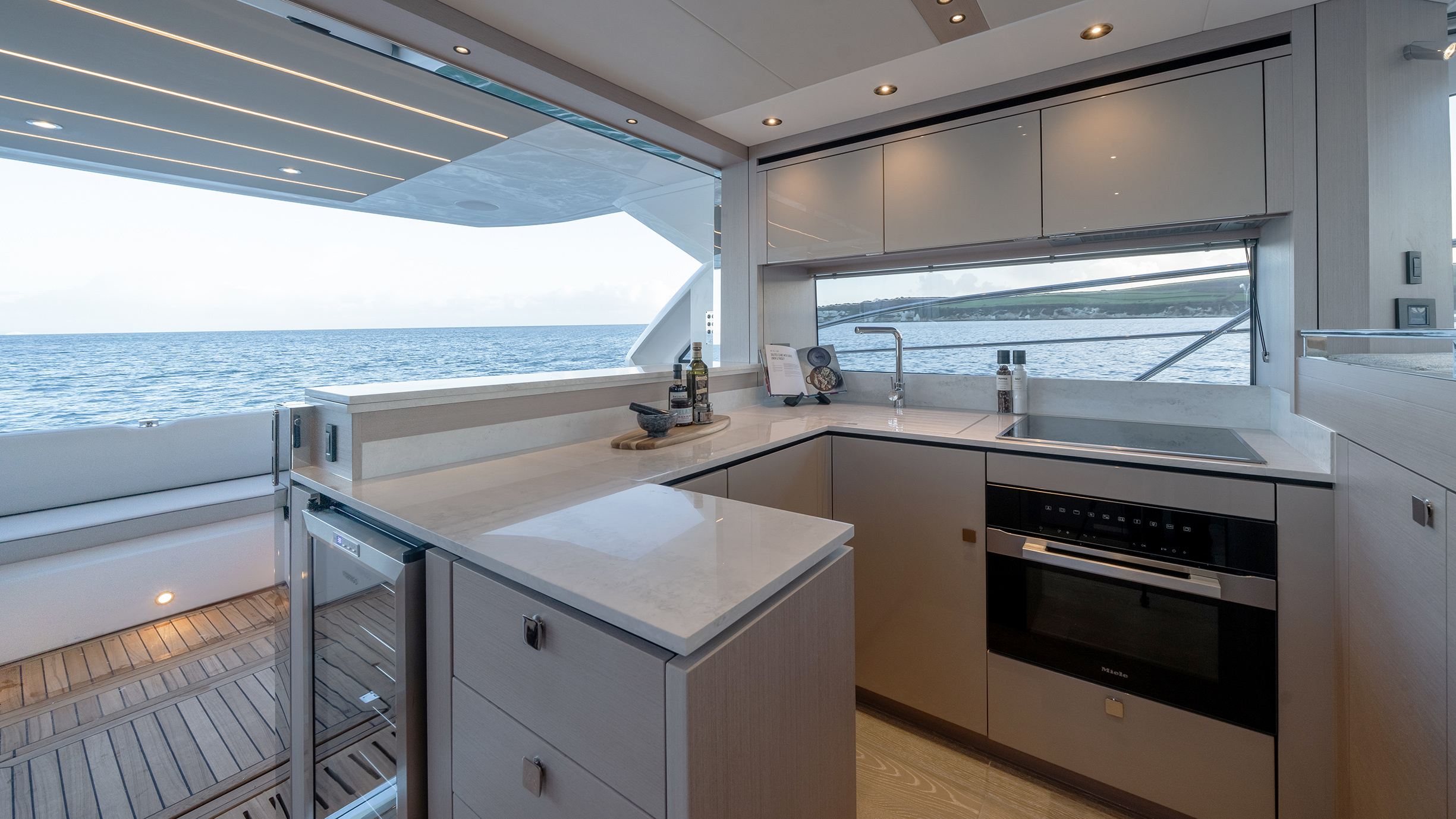 Sunseeker Manhattan 56 — galley at dusk, open to cockpit, ocean view beyond