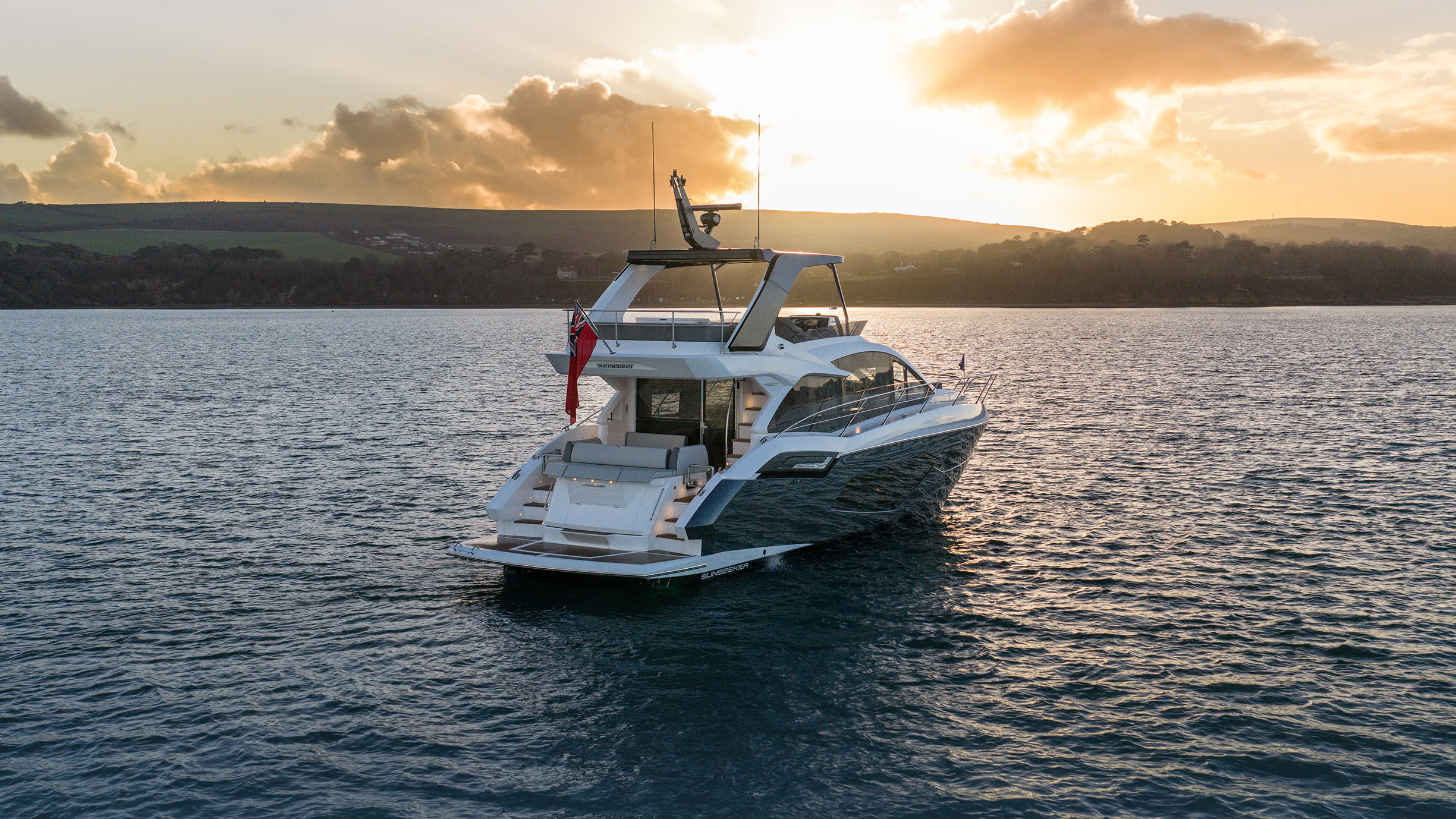 Sunseeker Manhattan 56 — starboard profile at rest, golden hour, Dorset coastline