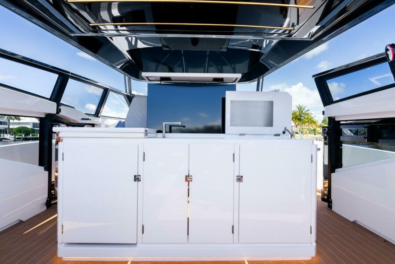 Sunseeker Superhawk 55 — helm side angle, display screens, joystick docking, teak accents