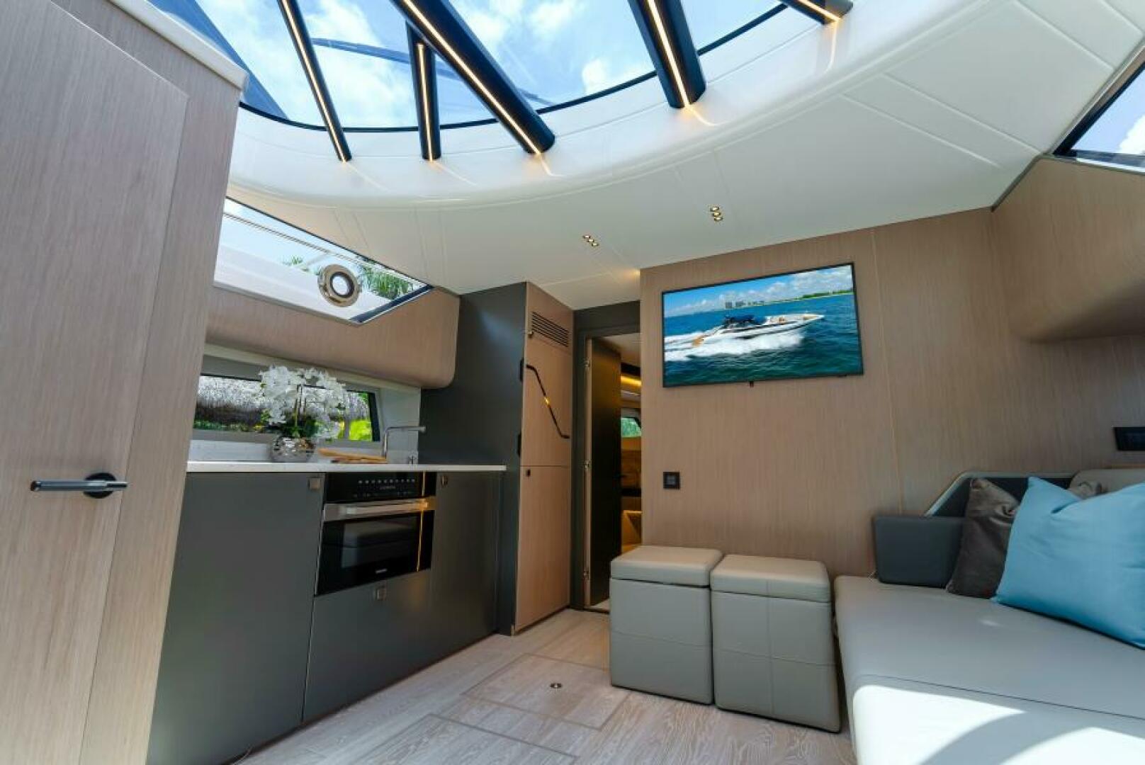 Sunseeker Superhawk 55 — saloon and galley, glass roof panel open, warm LED lighting